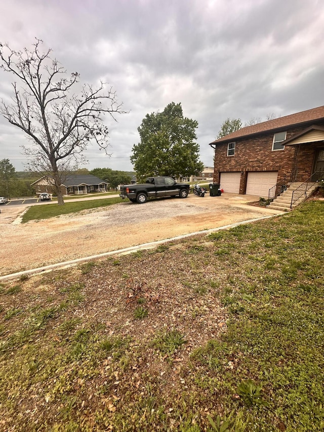 view of yard with a garage and dirt driveway