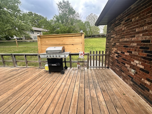 wooden terrace featuring a yard and a grill