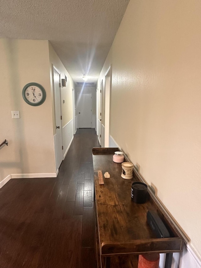 hall with baseboards, dark wood-style flooring, and a textured ceiling
