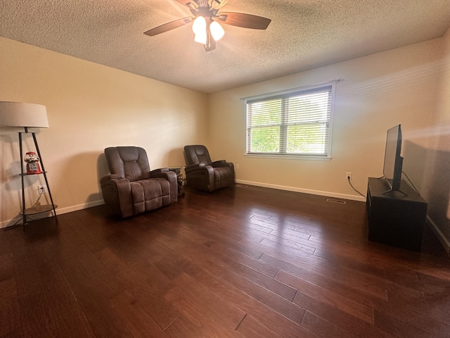 sitting room with a ceiling fan, a textured ceiling, dark wood-style floors, and baseboards