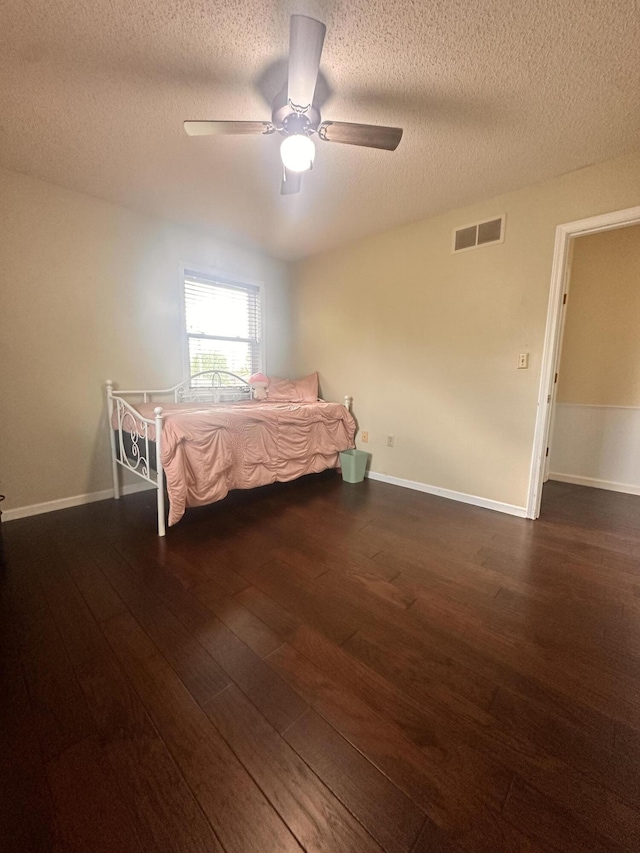 bedroom with visible vents, hardwood / wood-style floors, baseboards, a textured ceiling, and a ceiling fan
