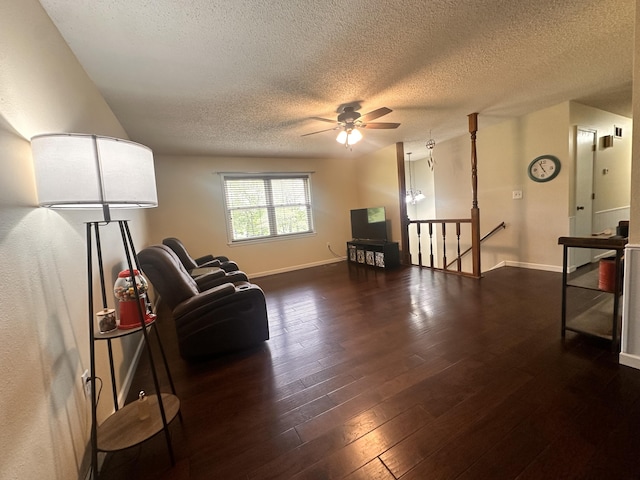 sitting room with a textured ceiling, dark wood finished floors, a ceiling fan, baseboards, and an upstairs landing
