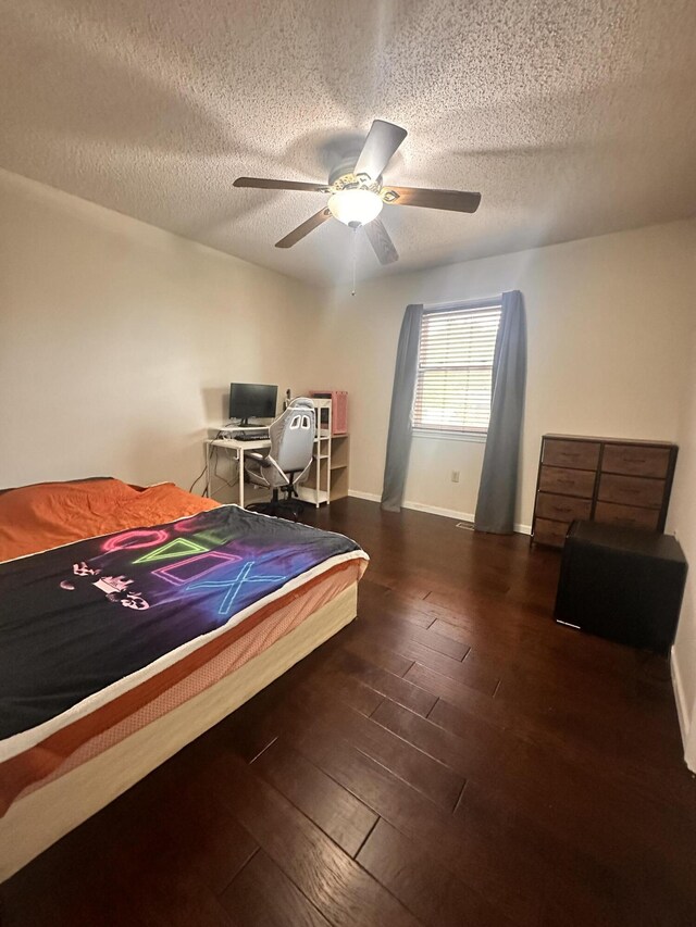 bedroom with hardwood / wood-style floors, baseboards, ceiling fan, and a textured ceiling