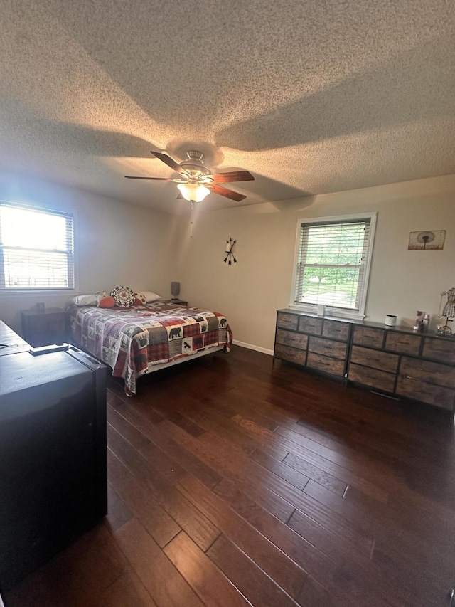 bedroom with wood-type flooring, a textured ceiling, and multiple windows