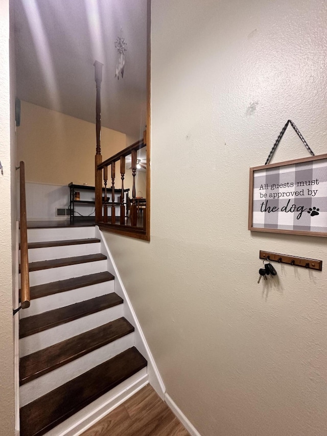 stairway with baseboards, wood finished floors, and visible vents