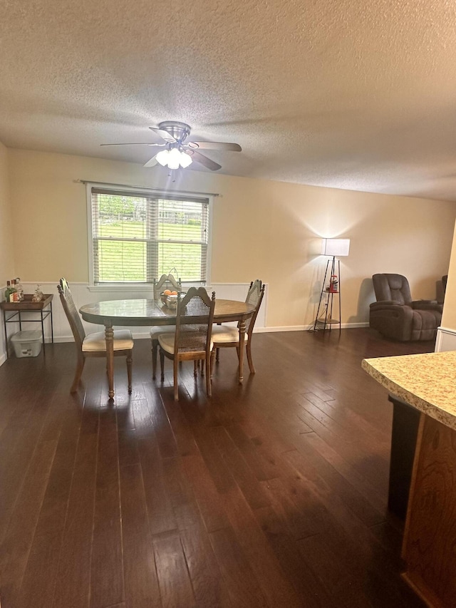 dining room featuring a textured ceiling, ceiling fan, dark wood-style floors, and baseboards
