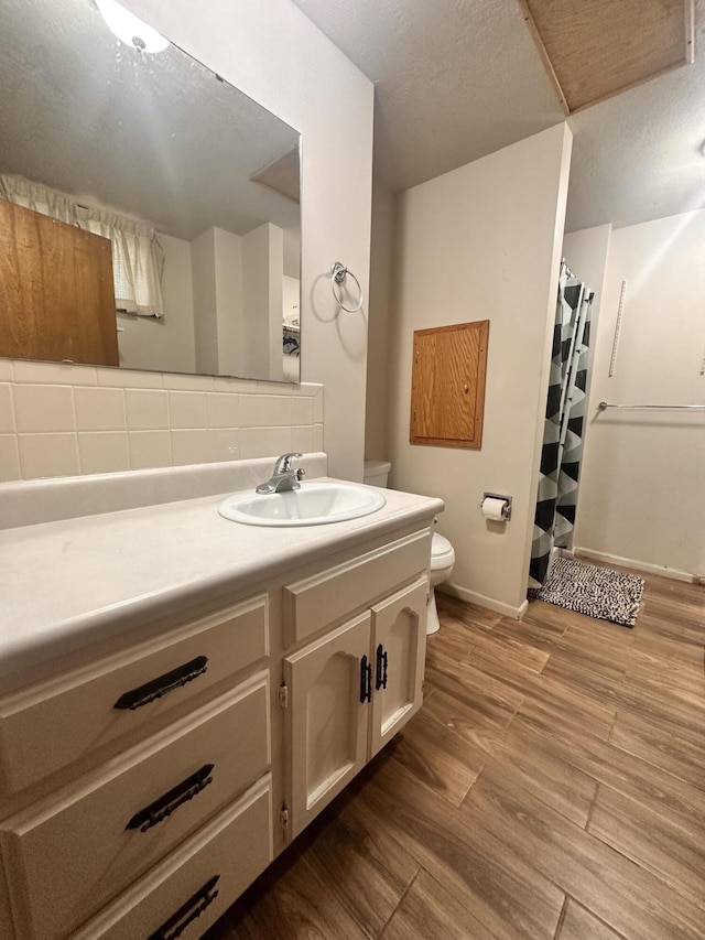 bathroom with vanity, wood finished floors, toilet, baseboards, and a shower with shower curtain