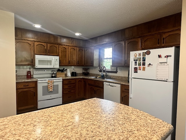 kitchen with white appliances, recessed lighting, light countertops, a textured ceiling, and a sink