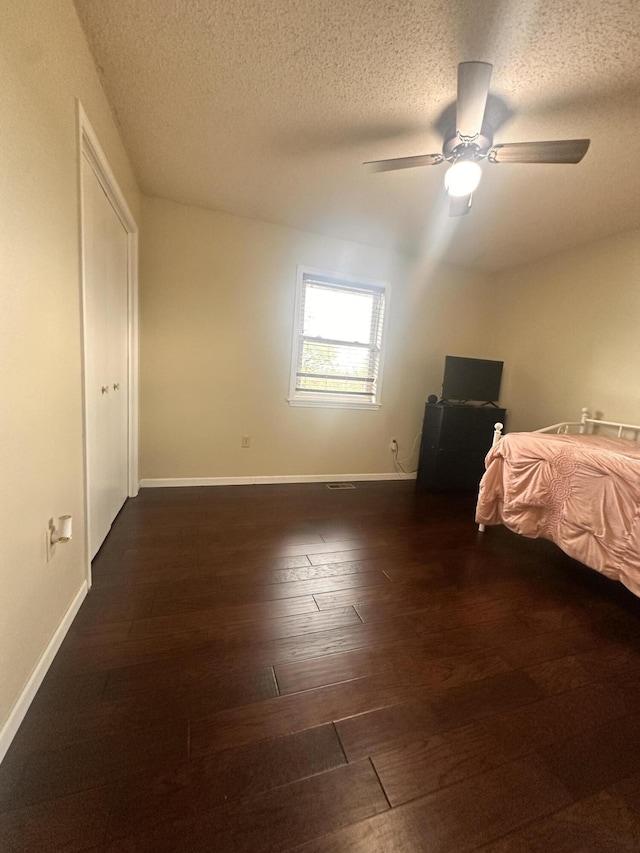 bedroom with hardwood / wood-style floors, baseboards, ceiling fan, and a textured ceiling