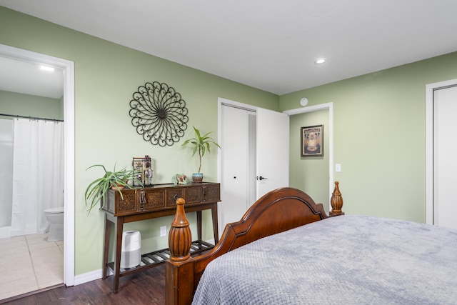 bedroom with baseboards, ensuite bathroom, recessed lighting, and wood finished floors