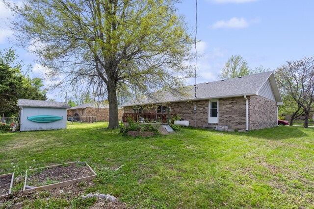 back of property featuring brick siding, an outbuilding, a garden, and a yard