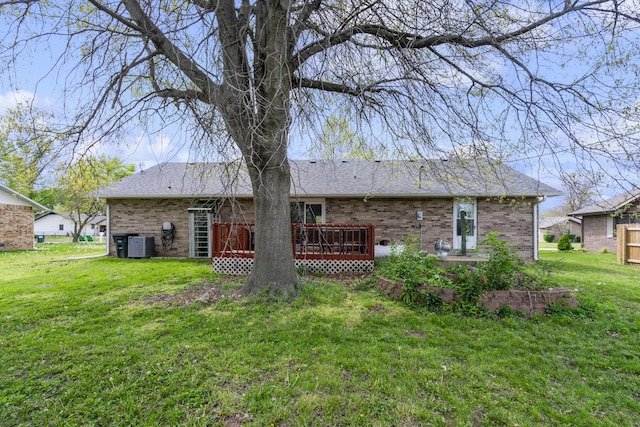 rear view of property featuring a wooden deck, cooling unit, a yard, and brick siding