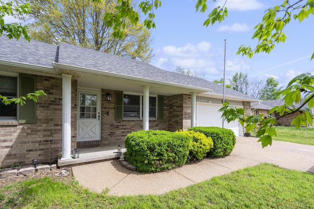 single story home featuring a porch, brick siding, roof with shingles, and a garage