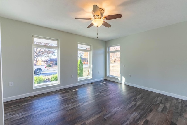 empty room with visible vents, a ceiling fan, dark wood-style flooring, and baseboards