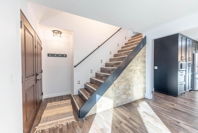 foyer featuring stairs, baseboards, and light wood finished floors