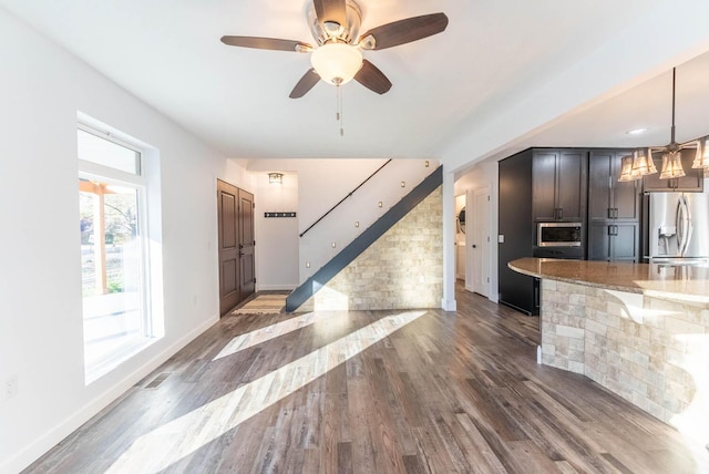 kitchen with light stone counters, baseboards, appliances with stainless steel finishes, and wood finished floors