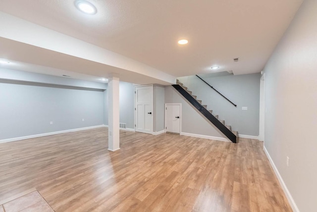 finished basement with light wood-style flooring, recessed lighting, baseboards, visible vents, and stairway