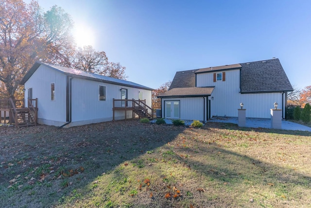rear view of house featuring french doors, a lawn, a deck, stairway, and a shingled roof
