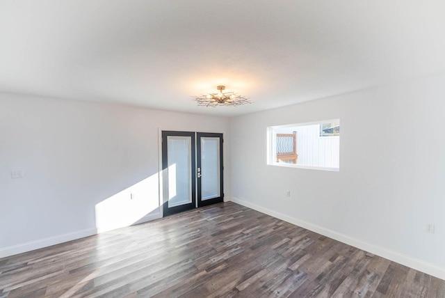unfurnished room featuring a chandelier, baseboards, and dark wood finished floors