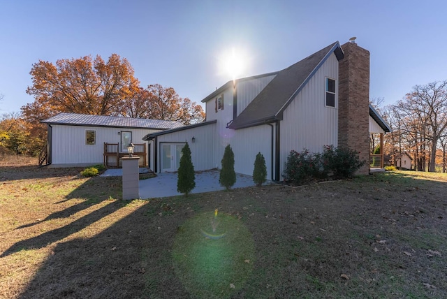 rear view of property featuring a chimney and a patio area