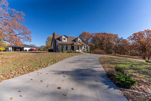 view of front of home featuring a front lawn, driveway, and a chimney