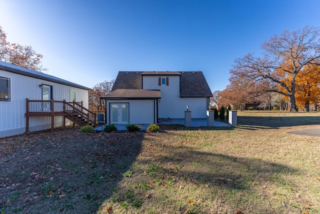 rear view of house featuring a deck, roof with shingles, french doors, a yard, and stairway