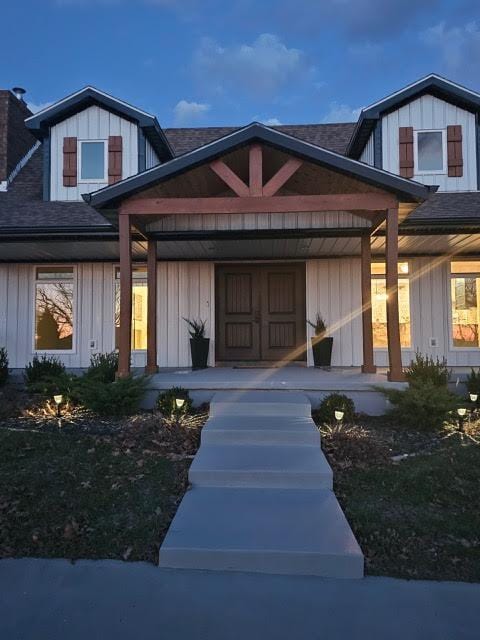 410 White Oak Dr, El Dorado Springs, MO 64744 - view of front of house featuring covered porch, a shingled roof, a chimney, and board and batten siding
