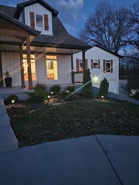 410 White Oak Dr, El Dorado Springs, MO 64744 - view of side of property featuring covered porch, a shingled roof, board and batten siding, and an attached garage