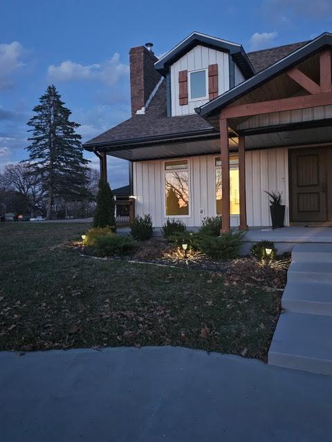 410 White Oak Dr, El Dorado Springs, MO 64744 - view of home's exterior featuring covered porch, a chimney, a shingled roof, and board and batten siding