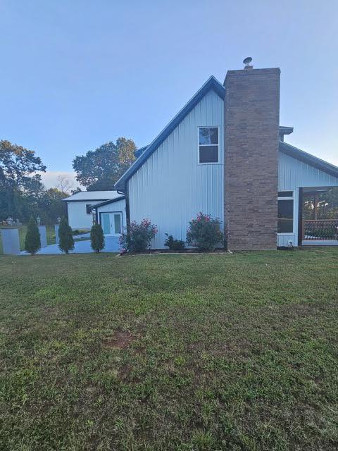 410 White Oak Dr, El Dorado Springs, MO 64744 - view of home's exterior featuring board and batten siding, a chimney, and a yard