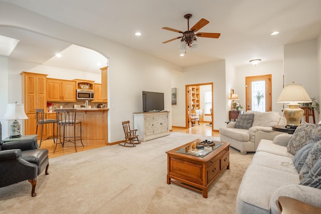 living area with recessed lighting, arched walkways, ceiling fan, and light carpet