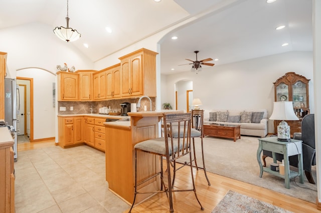 kitchen featuring a breakfast bar, arched walkways, a ceiling fan, recessed lighting, and a peninsula