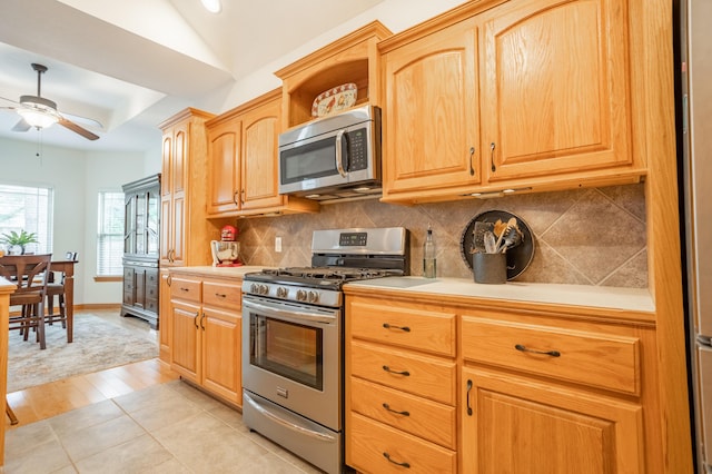 kitchen featuring appliances with stainless steel finishes, light countertops, a ceiling fan, lofted ceiling, and backsplash