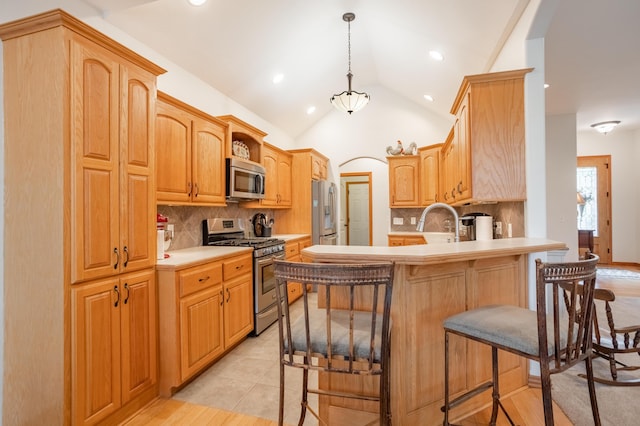 kitchen featuring a breakfast bar, stainless steel appliances, a peninsula, decorative backsplash, and lofted ceiling