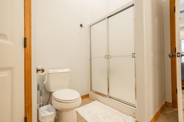 bathroom featuring tile patterned flooring, baseboards, a shower with shower door, and toilet