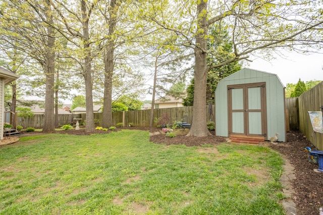 view of yard with a fenced backyard, a shed, and an outbuilding