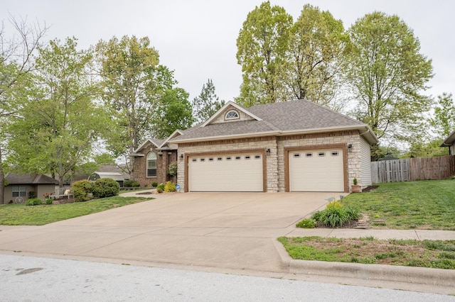 view of front facade featuring roof with shingles, a front yard, fence, concrete driveway, and an attached garage