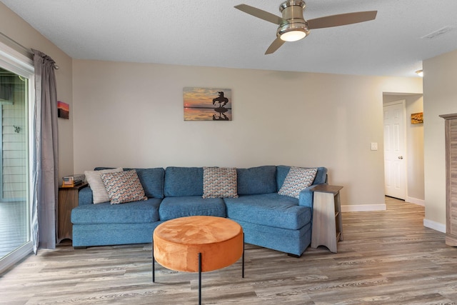 living room featuring baseboards, ceiling fan, visible vents, and wood finished floors