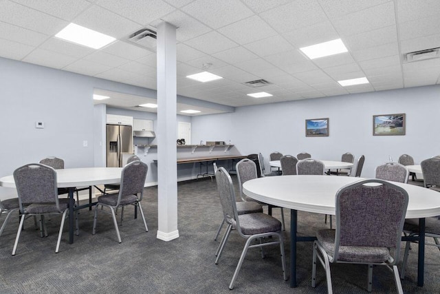 dining area with a drop ceiling, dark carpet, and visible vents