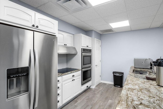 kitchen featuring a sink, light wood-style flooring, stainless steel appliances, white cabinetry, and under cabinet range hood