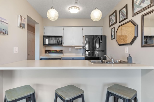 kitchen featuring a sink, white cabinets, black appliances, and a peninsula
