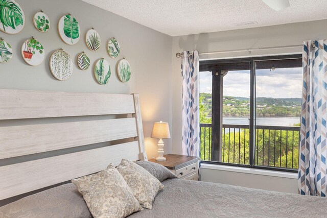 bedroom with a water view and a textured ceiling