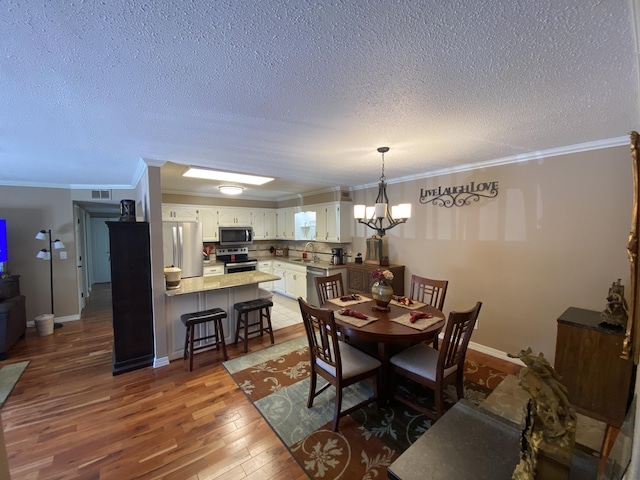 dining area featuring an inviting chandelier, crown molding, a textured ceiling, and light wood finished floors