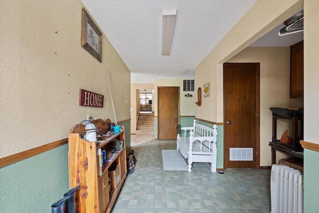 hall featuring radiator heating unit, tile patterned floors, stairs, and visible vents