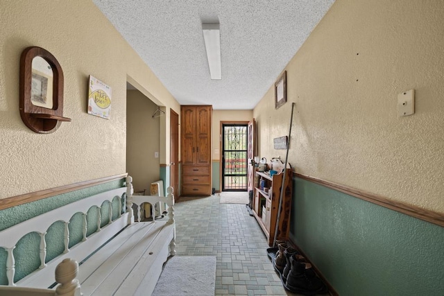 corridor with a textured ceiling and a textured wall