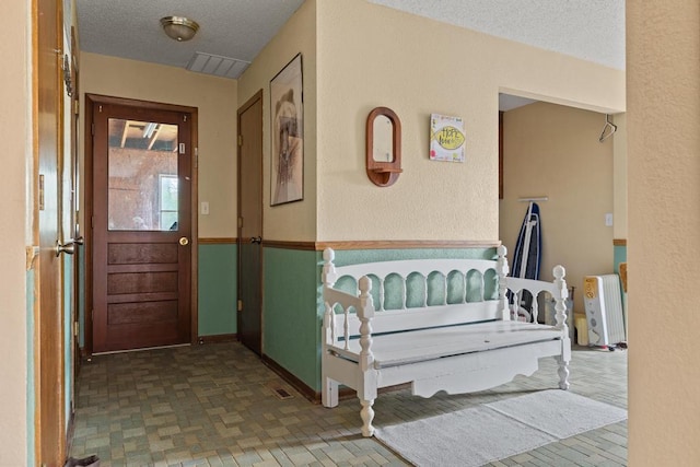 interior space featuring radiator, baseboards, a textured ceiling, and visible vents