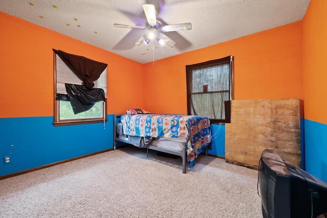 bedroom featuring baseboards, a textured ceiling, carpet, and ceiling fan