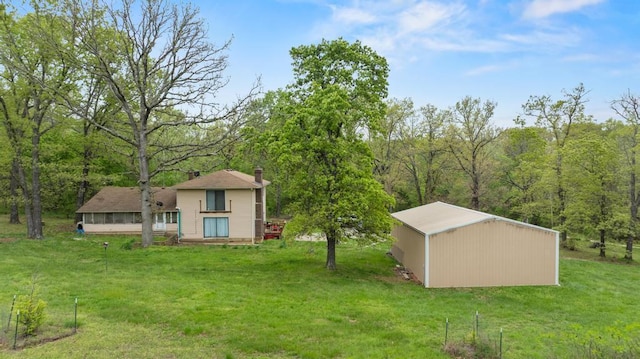 view of yard featuring an outdoor structure, a pole building, and a view of trees