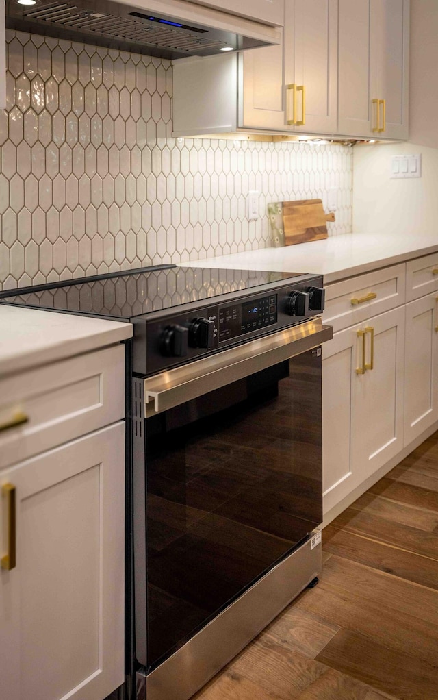 kitchen with light countertops, custom exhaust hood, range with electric stovetop, and dark wood-style floors