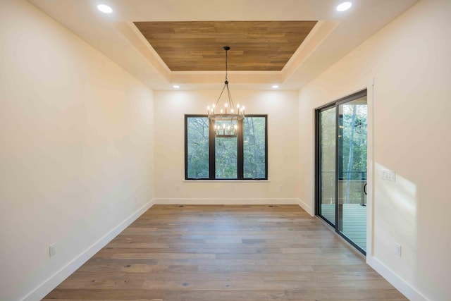 unfurnished dining area featuring wood finished floors, baseboards, a raised ceiling, wood ceiling, and a chandelier